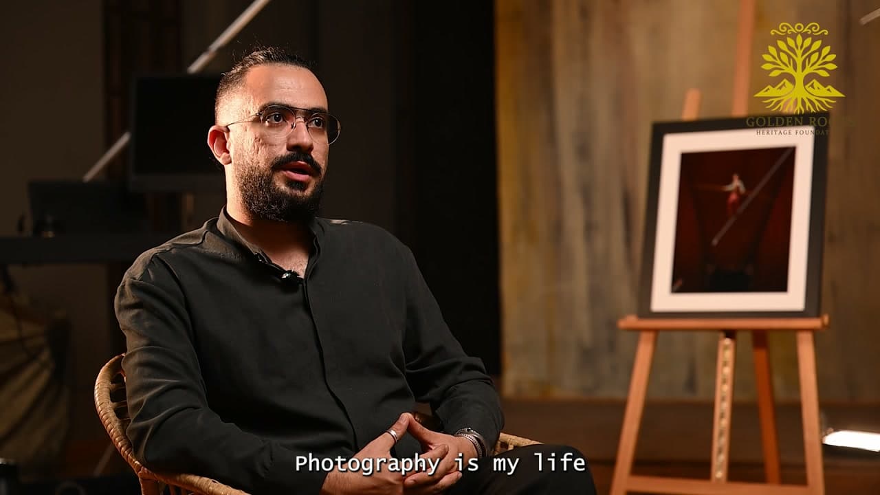 David Movsesyan speaking in the Golden Roots documentary, beside a framed photograph